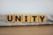 Time to unity symbol. Wooden cubes placed on a newspaper. The word `unity`. Beautiful wooden table. White background. Business a