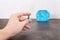 Time to using the Pill. Bright blue capsule pill in women hand on alarm clock background. Female hands holding one capsule