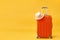 Time for travel, trip, adventure - an orange suitcase and a straw hat on a yellow background. Copy space