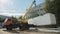 Timelapse auto crane transports white container near plant