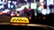 Timelapse of city traffic at night behind taxi sign