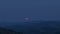 Timelapse close up rising moon red color on tops of mountains hills after sunset with a transition day to night moon changing colo