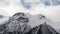 Timelapse close-up of the tops of snow-capped mountains on which clouds float. Mountain weather forecast