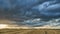 Timelapse clouds during sunset over field. A gray clouds with a thunderstorm across the sky with a visible rain band