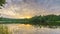 Timelapse of cloudy sunrise over forest lake