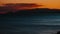 timelapse of a dramatic orange sunset over the sea with mountains
