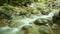 Timelapse fast stream of cold water of mountain river flowing between wet natural stones