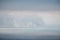 Timelapse of fluffy clouds moving in dark cloudy sky over calm sea and volcanic rocky shores. Abstract aerial nature