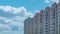 Timelapse fluffy white clouds in the blue sky and a high-rise apartment building. Cityscape. Slow movement of the camera