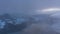 Timelapse foggy sunset in snowy mountains covered with clouds. Sunrays above the mountain. Walensee. Aerial view on Kerenzerberg,