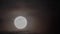 Timelapse - full moon rising against black sky with moving clouds at night