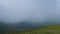 Timelapse of a herd of horses grazing on a mountain slope under low cloudiness against the background of rocks