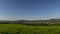 Timelapse landscape view from field on city and surrounding mountains and hills during the day with moving clouds on the horizon V