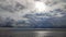 Timelapse. Large rain clouds move in sky above the sea surface on a sunny day.