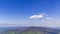 Timelapse of the mountain top peaks and the surrounding landscape above which form white clouds changing shape and reflecting shad