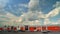 Timelapse movement of cars and people in a large parking lot. Beautiful fluffy clouds float over a shopping mall