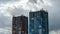 A timelapse of the movement of gray rainy clouds over two beautiful modern multi-storey buildings. Urban landscape