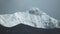 Timelapse of the onset of night on a snowy peak. clouds swirl over the summit of Mount Nilgiri