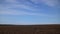 timelapse of plowed field and blue sky, soil and clouds of a bright sunny day - concept of agriculture