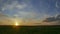 Timelapse of running clouds across the blue sky in a field at sunset.