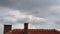 Timelapse of the sky with dramatic clouds and the roof of the house on summer day