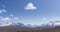Timelapse of sun movement on crystal clear sky with clouds over snow mountain top. Yellow grass at autumn high altitude