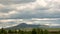 Timelapse thick clouds float over a green mountain peak and a beautiful evergreen national park