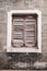 Timeless Elegance: Wooden Shutter of an Old Broken Window Against a Weathered Brick Wall