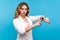 Times up! Portrait of serious woman pointing at watch on hand and looking disapprovingly. blue background