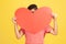 Timid man in red striped t-shirt shyly peeking out from big red paper heart, showing his feelings, making surprise on valentines