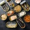 Tin can of Saury, mackerel, sprats, sardines, pilchard, squid, tuna Open and closed over black slate background top view square