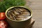 Tin can with tasty sprats served on wooden table, closeup