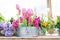 Tin flower pots with a floral arrangement of tulips and other flower varieties in pink, white, yellow and bright green stems.