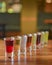 Tincture alcoholic in small shot glasses. Natural fruit alcohol drinks, shots served on a wooden table