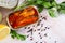 Tinned sardines in tomato sauce on background with greens and lemon