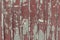 A tinny fence background painted red. Abstract detailed texture. An old weathered surface with damages.