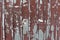 A tinny fence texture painted red. An old weathered surface with damages. Abstract background with detailed texture.