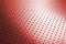 Tinted red metal background with saturated color. Dark horizontal wallpaper. Perforated aluminum surface with many holes. Their