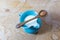 Tiny blue ceramic pitcher of almond milk, centered, wood spoon with a single almond balanced over top