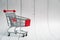 Tiny empty shopping cart on on white wooden background