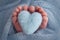 The tiny foot of a newborn baby Soft feet of a new born in a light blue blanket.Knitted blue heart in the legs of a baby