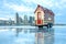 tiny house on a reflective glass surface with skyline in the background