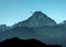 Tiny mountain climber scaling a snow covered hill being rescued by a rescue helicopter. Sky background with space for copy.