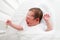 Tiny new born baby screaming in white round crib