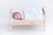 Tiny newborn baby sleeping in a toy crib