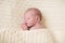 Tiny newborn baby sleeping under knitted blanket