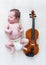 Tiny newborn girl lying next to a violin