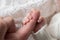 Tiny newborn hand holds father& x27;s finger