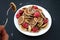 Tiny pancake cereal - trendy quarantine food. Person eating mini pancakes in bowl with fresh raspberries and coconut flakes on