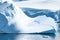 Tiny Penguins on Ice Floe and on Huge Iceberg with Fissure in Antarctica near Petermann Island